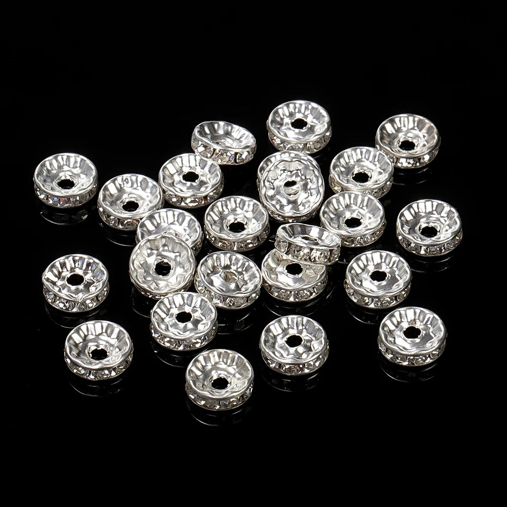 A collection of silver crystal rondelle spacer beads for jewelry making arranged on a black surface.