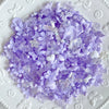 A pile of purple and white Y2K acrylic bow and flower beads for DIY jewelry making