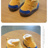 A pair of mustard yellow plush-lined winter boots for toddlers resting on a wooden surface.