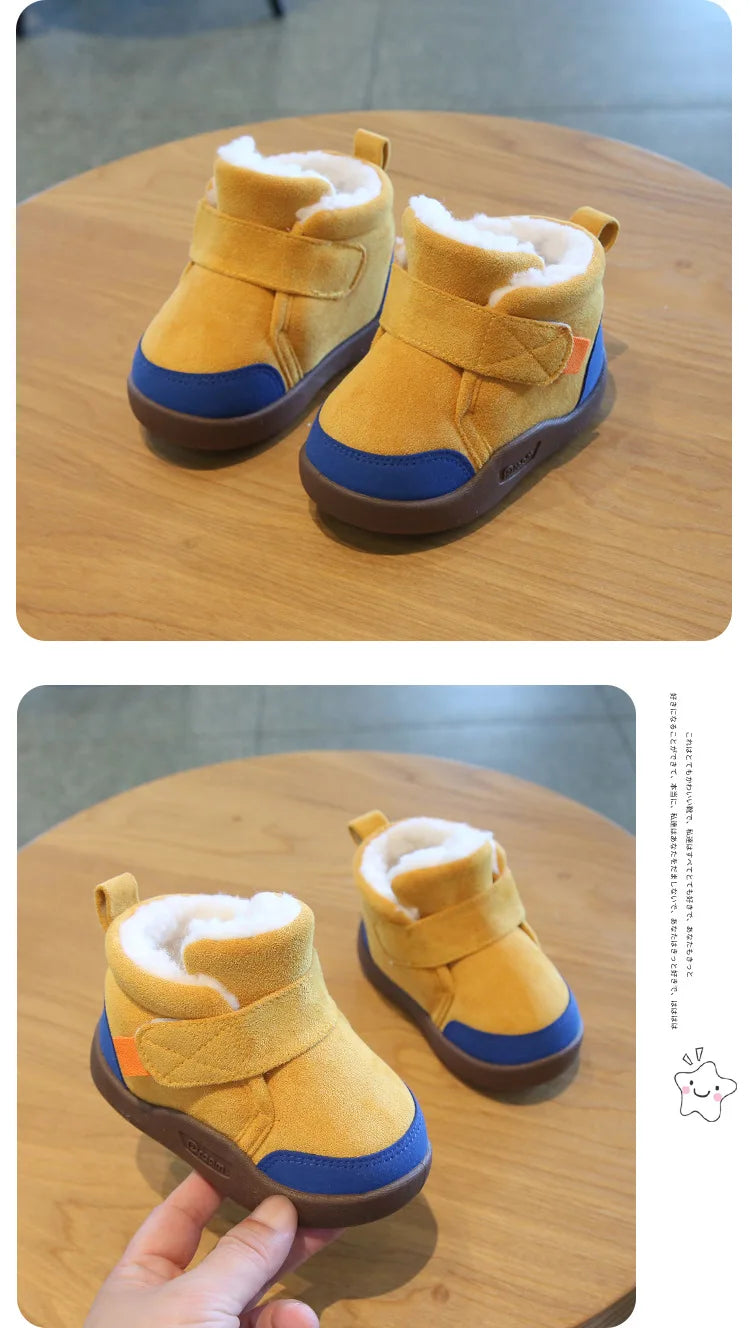 A pair of mustard yellow plush-lined winter boots for toddlers resting on a wooden surface.