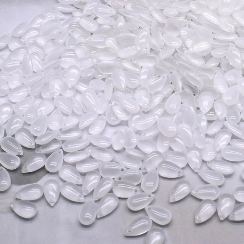 A pile of clear, teardrop-shaped water drop Czech glass beads for jewelry making.