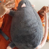 A gray plush rat with a pink branch is being held by a person.