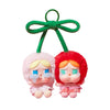 A blind box featuring two chibi-style vinyl figures with pink and red hair and blue eyes, suspended by a green ribbon.