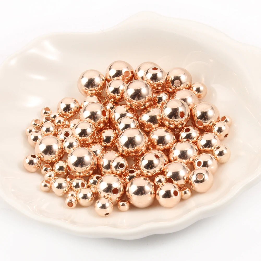 A pile of small, round, rose gold spacer beads on a white dish.