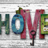 Wooden letters spelling LOVE HOME with a key on a distressed white wooden background