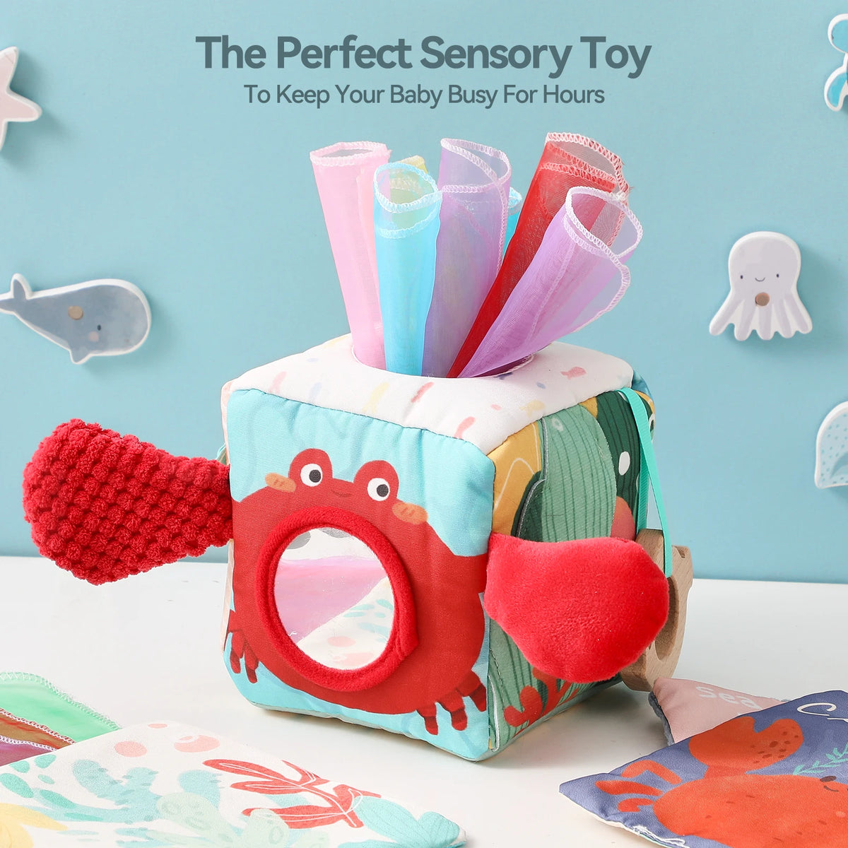 A colorful tissue box sensory toy for babies featuring an ocean theme and cloth book.