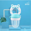 A white silicone baby food feeder with a teal lid and a green teether is displayed on a light blue background.