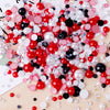 A colorful mix of red, pink, black, and white resin rhinestones and pearls for craft and nail art projects.
