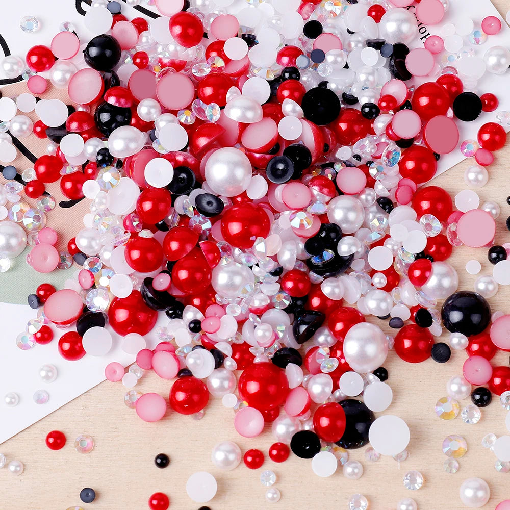 A colorful mix of red, pink, black, and white resin rhinestones and pearls for craft and nail art projects.