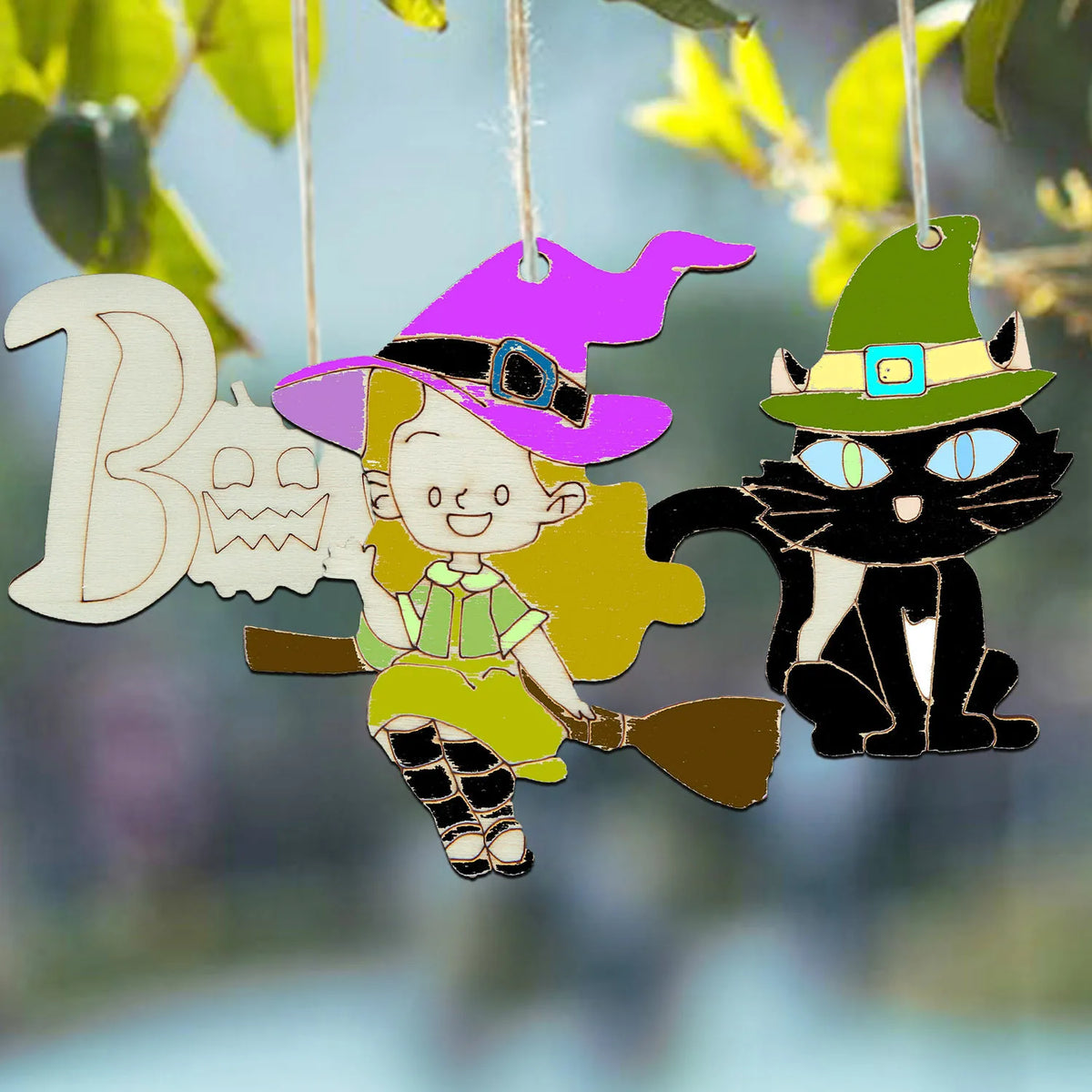 Wooden hanging ornaments featuring a smiling girl and a black cat wearing witch hats