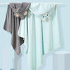 A light mint green hooded animal bath towel hanging on a hanger.