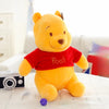 A yellow Winnie the Pooh plush toy sitting on a white surface.