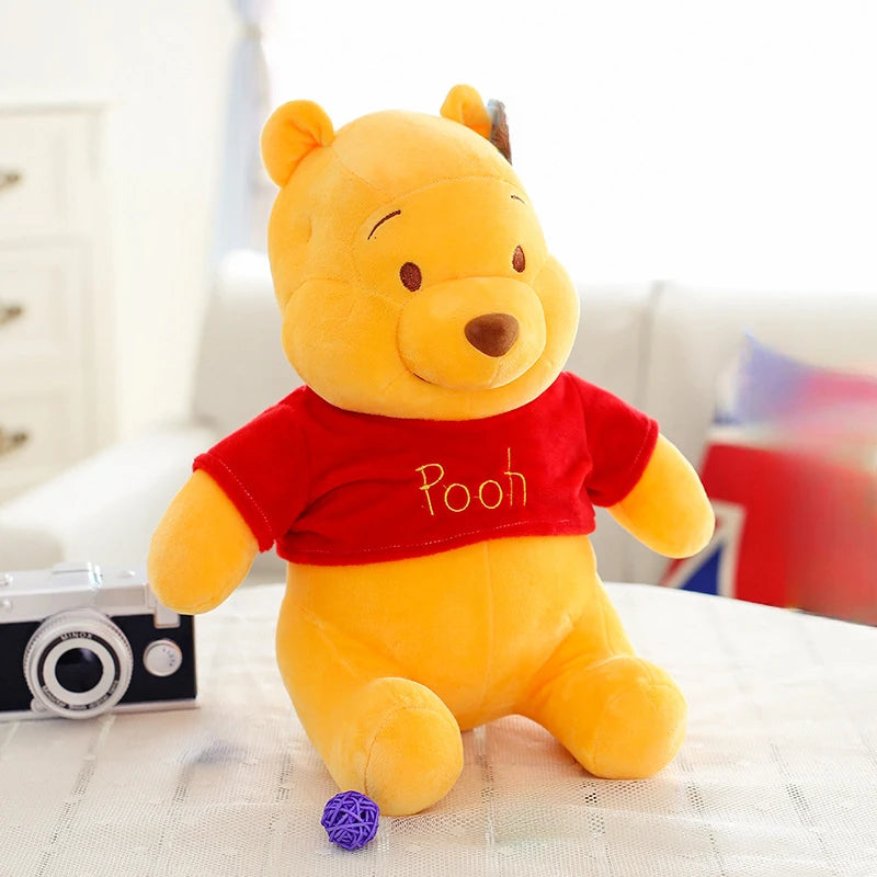 A yellow Winnie the Pooh plush toy sitting on a white surface.