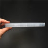 A hand holds a clear plastic storage box with internal dividers for jewelry and craft supplies against a dark background.