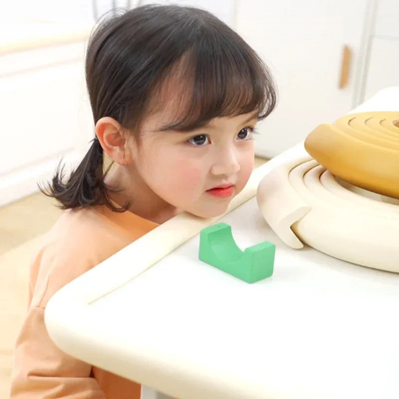 Une jeune fille interagit avec un pare-chocs de coin de table blanc, pièce en plastique vert.