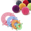 An assortment of colorful pom-pom making tools and yarn balls in various shades like purple, yellow, pink, and green.