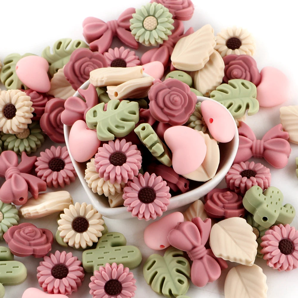 A collection of pink and green silicone flower and leaf beads for jewelry making