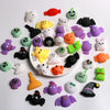 A collection of colorful Halloween squishy toys including orange, purple, green, and black figures on a white background.