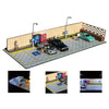 A 1:64 scale LED miniature car garage diorama showing several cars parked in an outdoor lot with a brick wall background.
