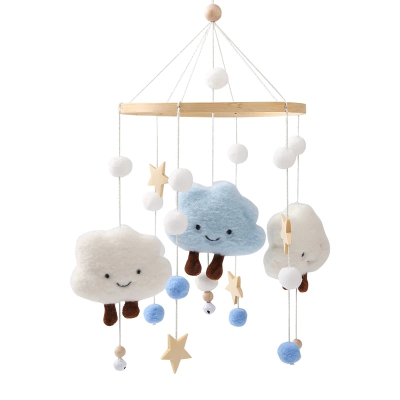 A wooden rattle and mobile pendant featuring soft white clouds and blue accents hanging from strings.