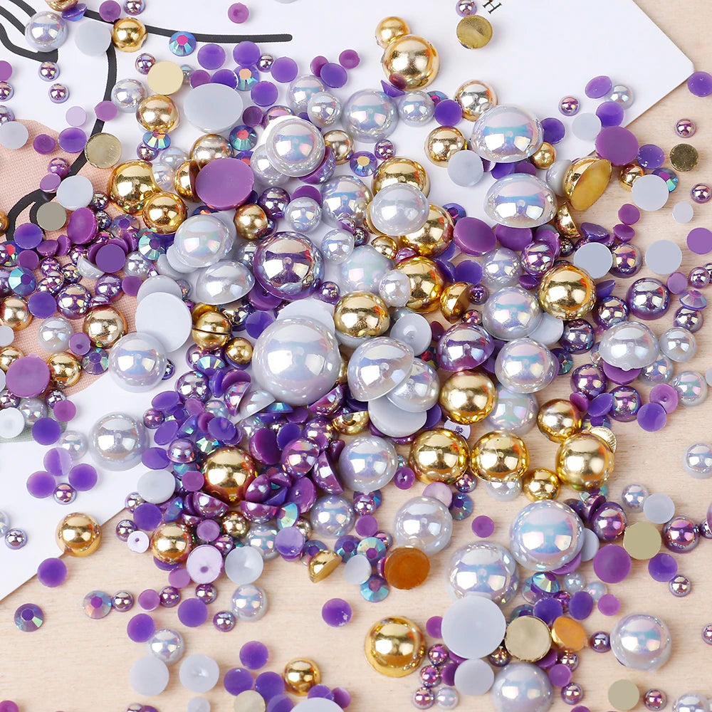 A scattered collection of mixed resin rhinestone pearls with an AB finish in various shades of purple, silver, and gold.