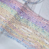 A long strand of multicolor aurora cut glass beads in shades of pink, purple, and iridescent white.