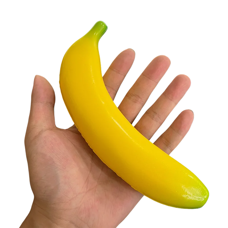 A hand is holding a bright yellow squishy banana stress relief toy.