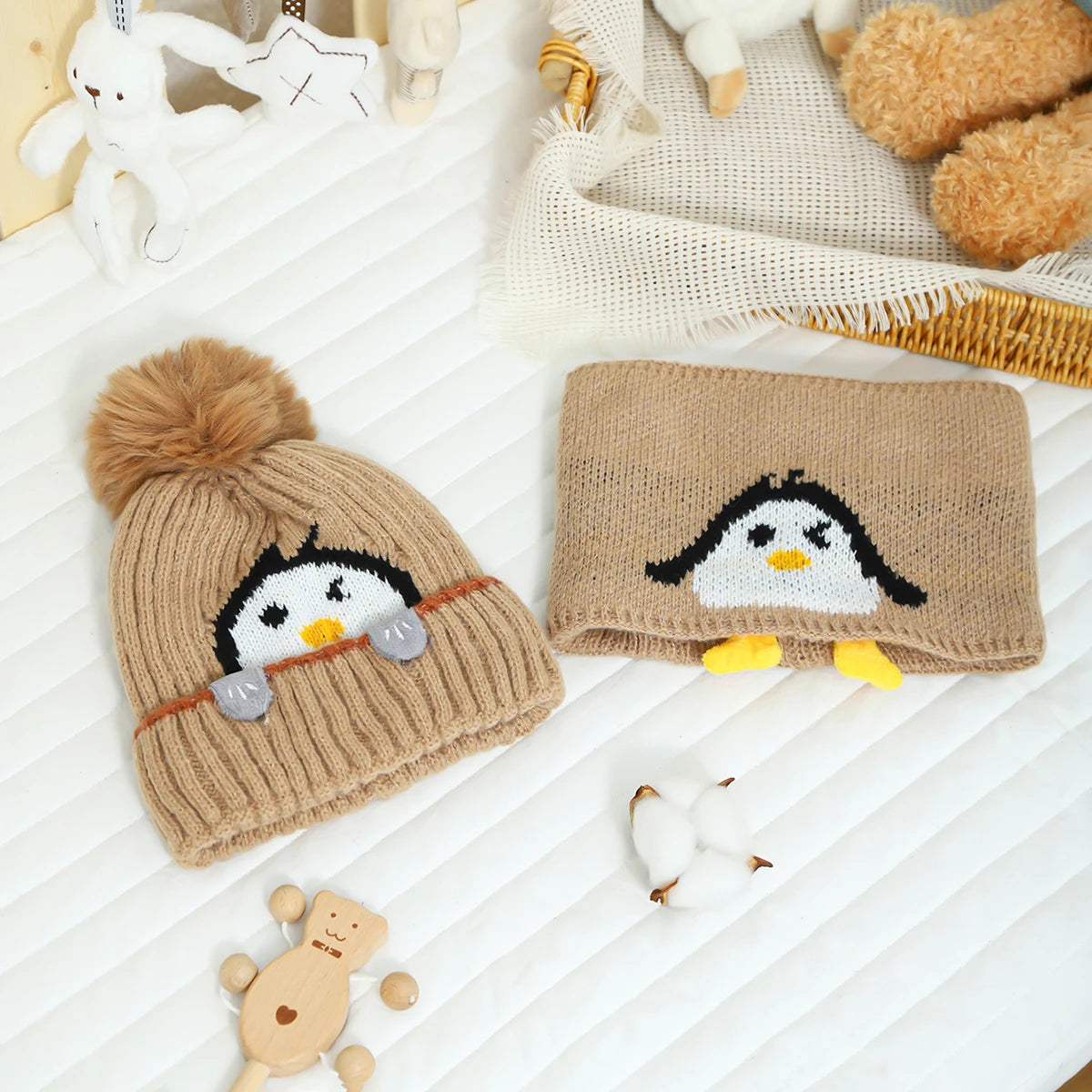 A knitted penguin hat and scarf set featuring black and white designs on a beige background