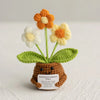 Handmade crochet sunflower plant with yellow flowers and green leaves growing from a brown pot.