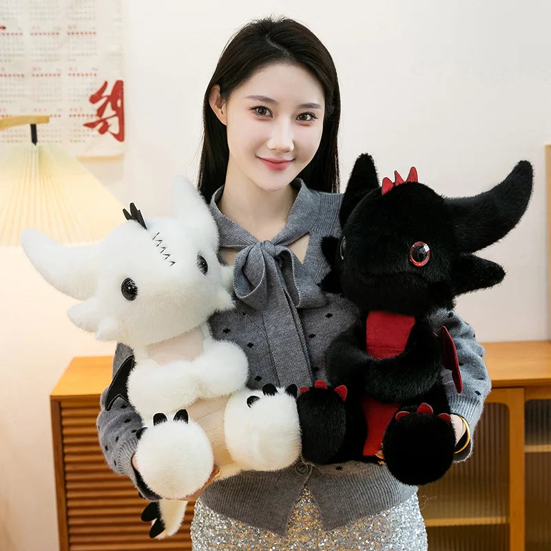 A woman holds a black Toothless dragon plush toy with red accents and a white dragon plush toy.