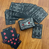 A stack of black and white poker cards is displayed on a wooden surface.