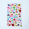A colorful arrangement of various clear and colored acrylic gem stickers for face, nails, and crafts