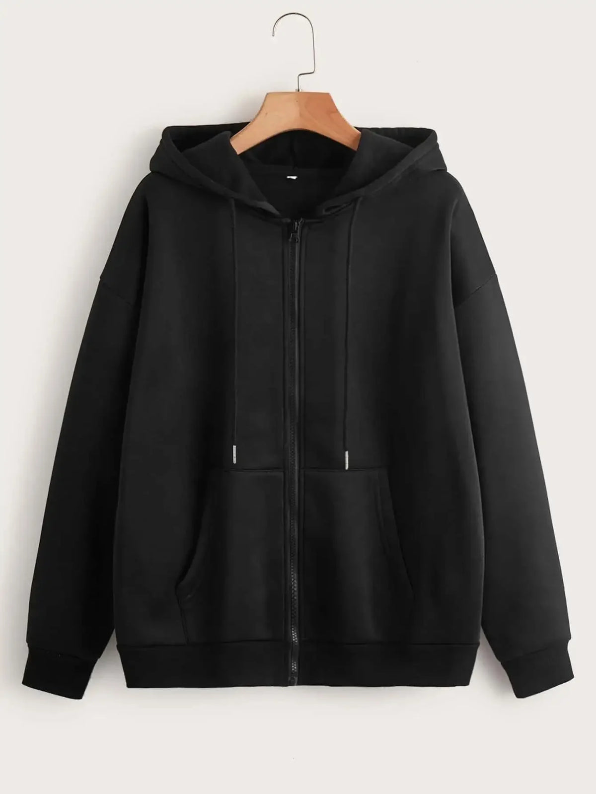 Black oversized zip-up hoodie with a front pocket hanging on a hanger.