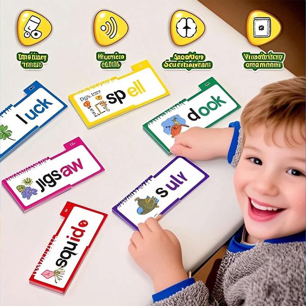 A young boy is smiling while looking at various phonics flip books and sight word flash cards laid out on a white table.