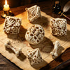 A set of bone skull carved polyhedral dice resting on an old map and wooden surface.