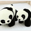 A white and black panda plush pillow lying on a white surface.