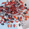 A pile of reddish-orange and clear glass water drop beads for jewelry making