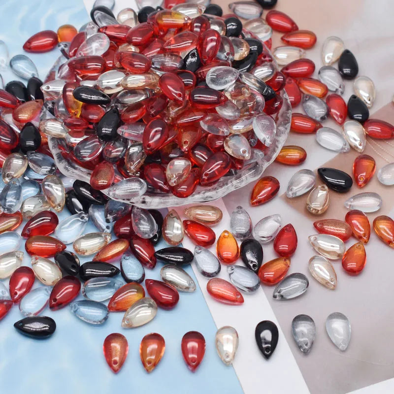 A pile of reddish-orange and clear glass water drop beads for jewelry making