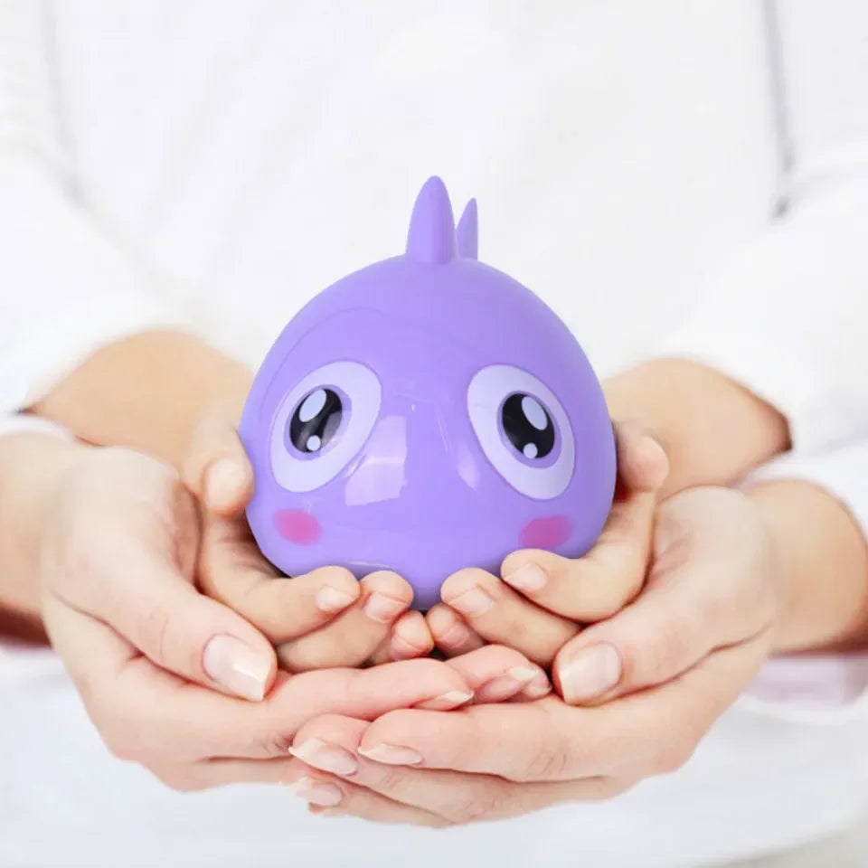 A purple wind-up swimming turtle bath toy is held in cupped hands against a white background.