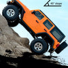 Orange 1:18 scale RC Jeep climbing a rocky slope at a 45-degree angle