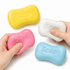 Hands hold various yellow, pink, and blue soap-shaped squishy stress relief toys.