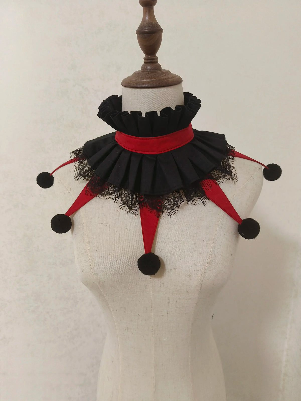 A black and red ruffled collar accessory displayed on a white mannequin.