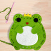 A green felt frog craft kit with a yellow crown and a pink string, ready for a beginner DIY project.