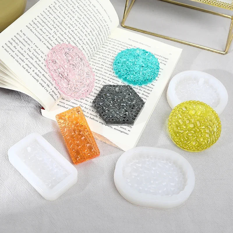 A set of flexible silicone resin molds in various colors and shapes for DIY jewelry making, displayed next to an open book.