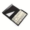 A black domino set box with an open lid displaying 28 white and black domino tiles.