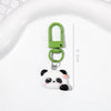A small, cute white and black panda charm keychain with a green metal clasp.