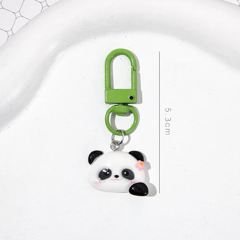 A small, cute white and black panda charm keychain with a green metal clasp.