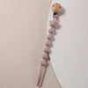 A silicone pacifier clip featuring a wooden bear paw and pink silicone beads on a thin pink cord.