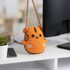 Handmade crochet orange tiger hanging ornament with black eyes displayed on a white surface.