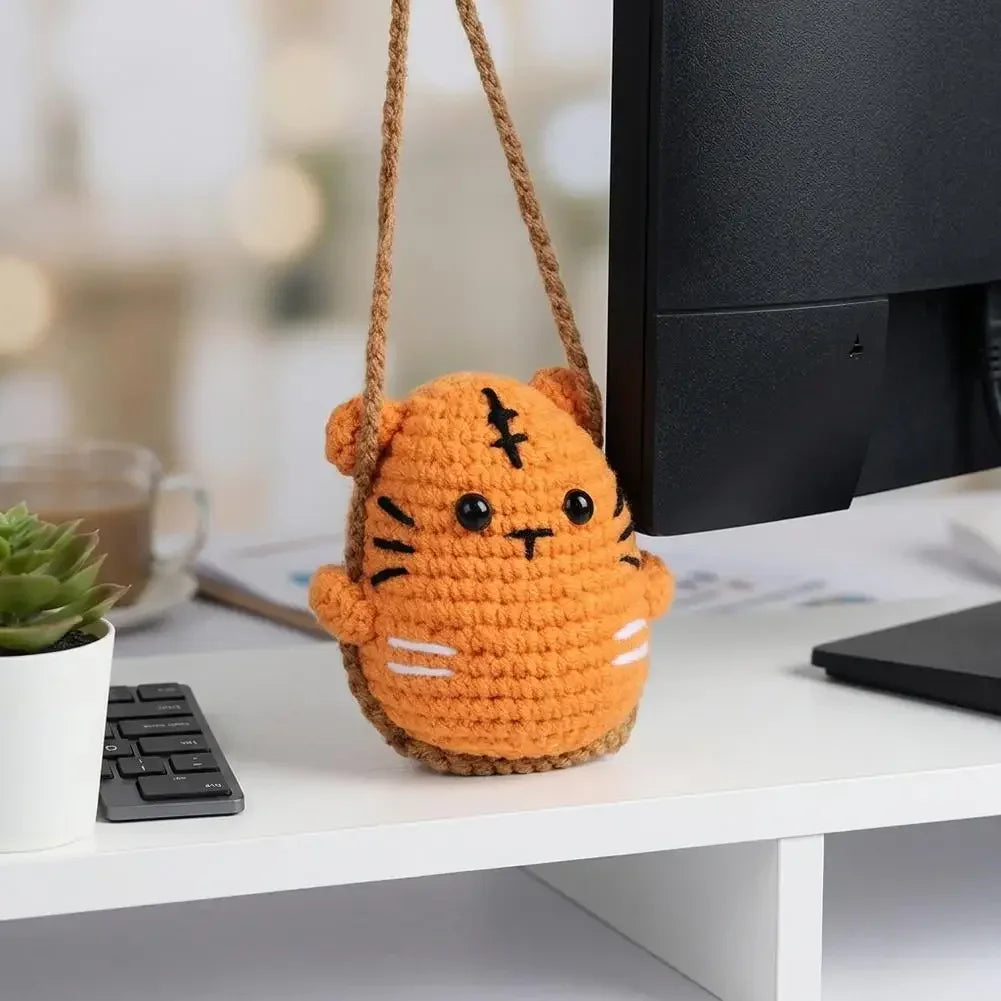 Handmade crochet orange tiger hanging ornament with black eyes displayed on a white surface.